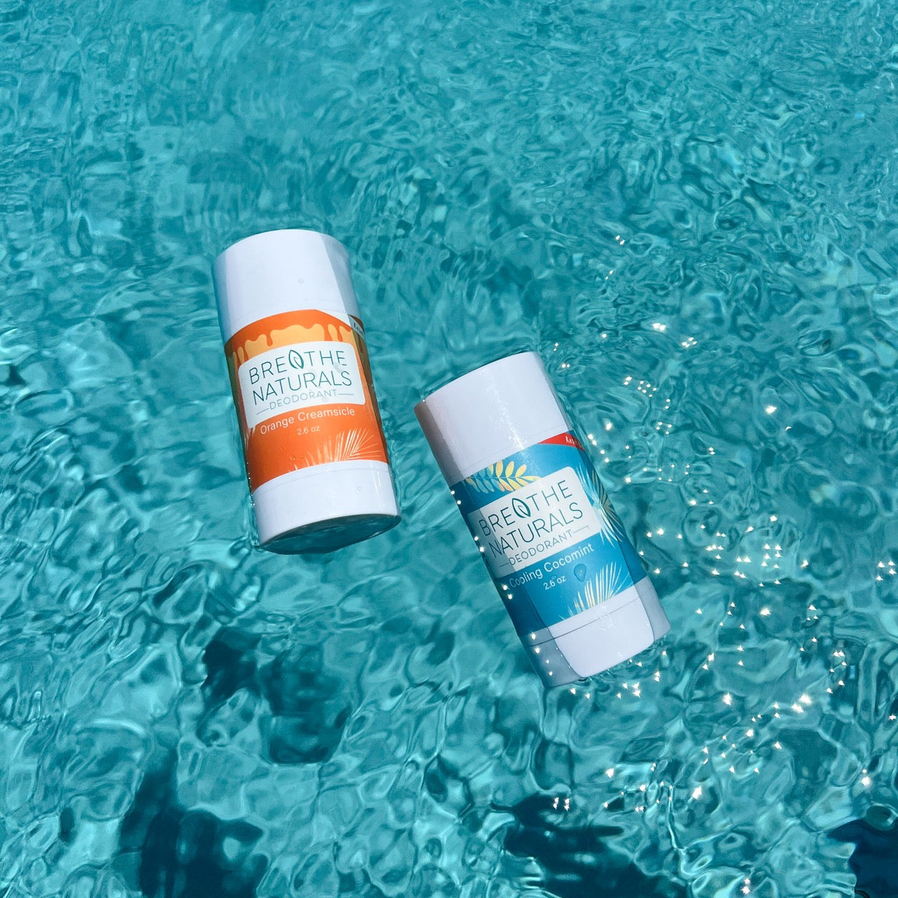 Two deodorant sticks from 'Breathe Naturals' floating in clear blue water.